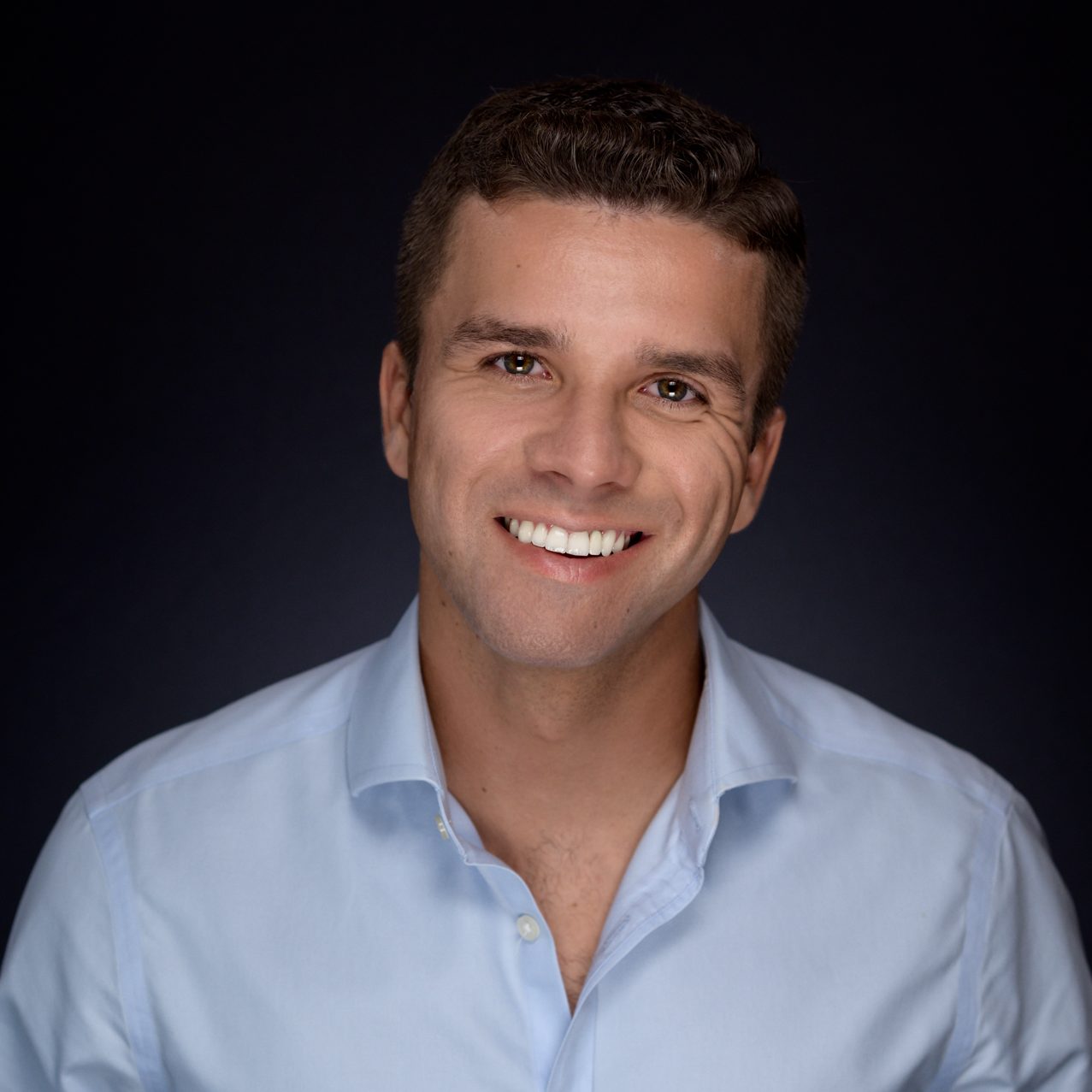Male Headshot on a gray to black background.