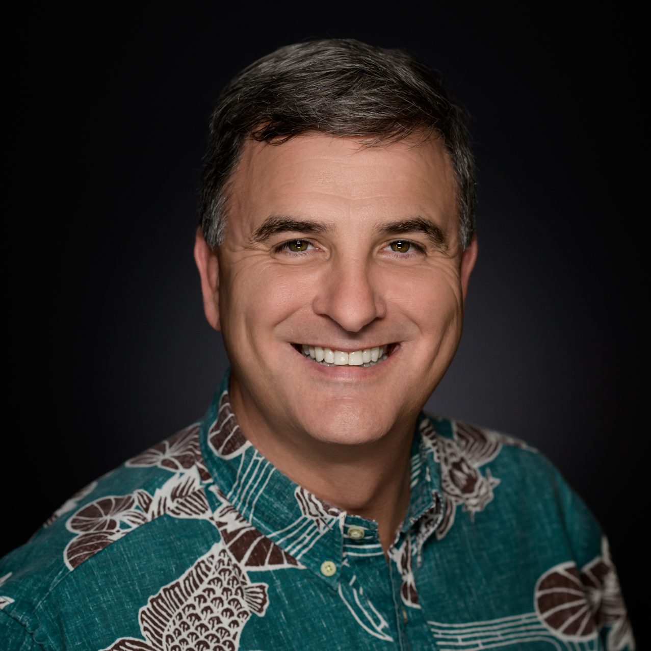 Male Headshot on a gray to black background.