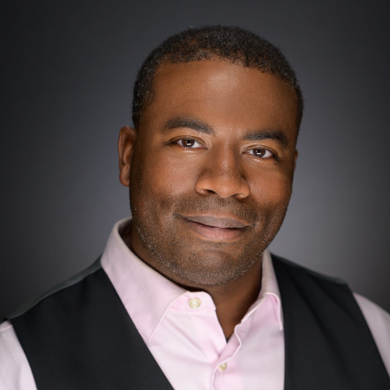 Male Headshot on a gray to black background.