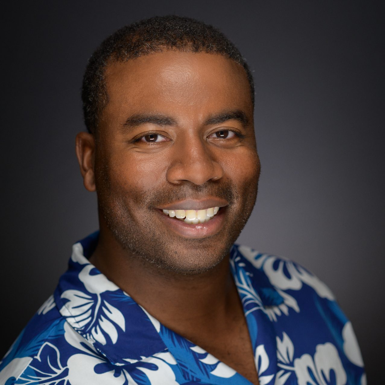 Male Headshot on a gray to black background.