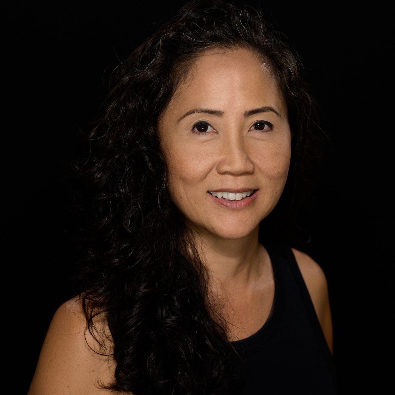 Female headshot on a pure black background.
