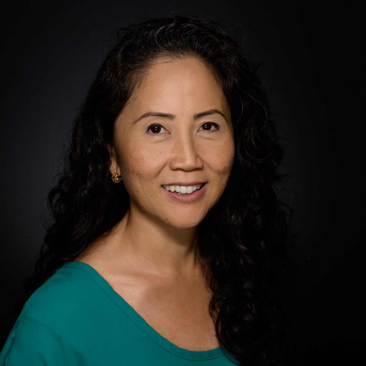 Female headshot on a gray to black background.
