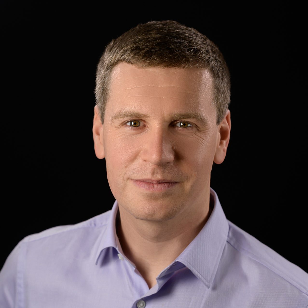 Male headshot on a pure black background.