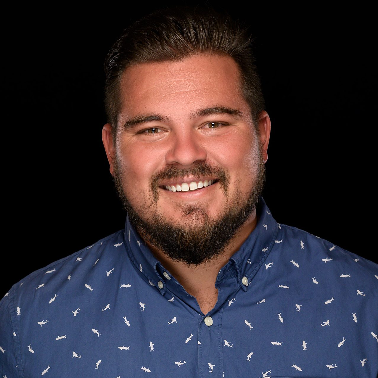 Male headshot on a pure black background.